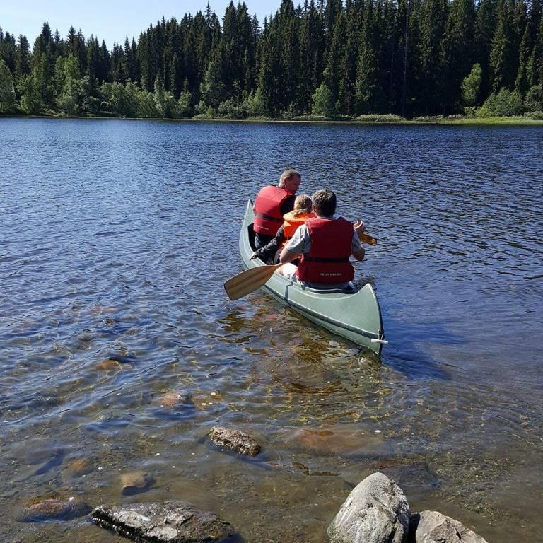tre som padler i en kano på et vann