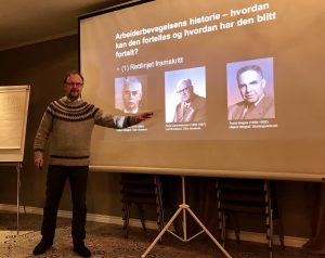 bilde av en mann som holder foredrag og peker på bilder på et lerret