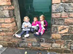 tre jenter som sitter i en vinduskarm og spiser is