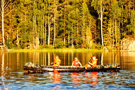 tre barn padler kano, alle har på seg redningsvest